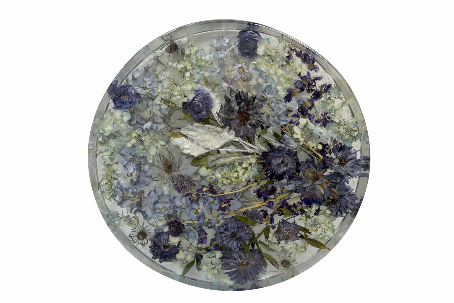A circular glass bowl filled with water and floating dried blue, purple, and white flowers and leaves.