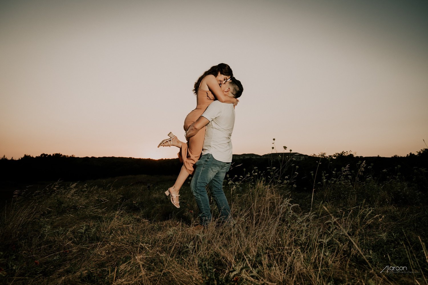 A couple laughing together during their engagement portraits at sunset