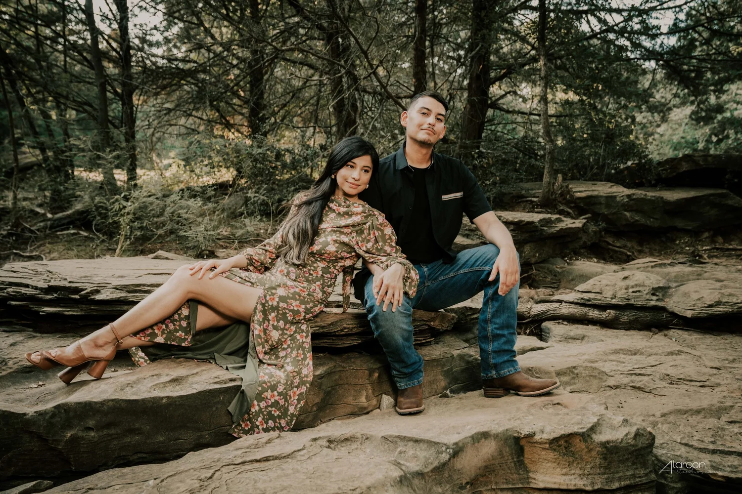 A couple relaxing together among trees and rocks during their portrait session
