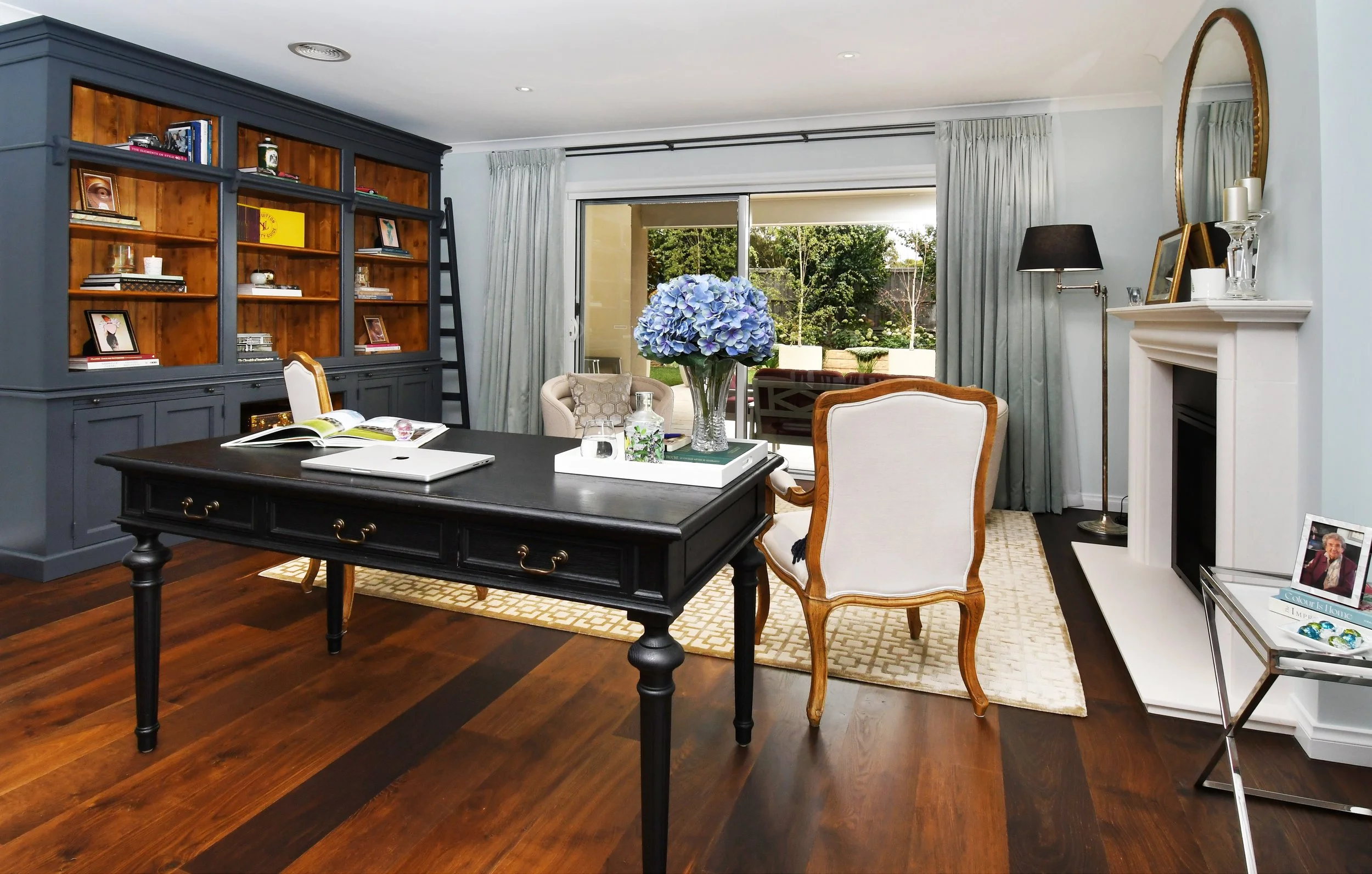 Interior view of Cloudview living room with oak flooring, classic black desk and library style bookcase