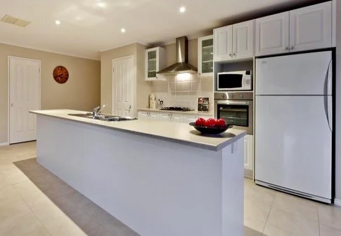 The kitchen is the heart of the Georgian Home and the white traditional cabinets and soft white marble look bench tops give it a light and airy feeling. The walk in pantry provides plenty of room for staples and treats on offer in this bright, open s