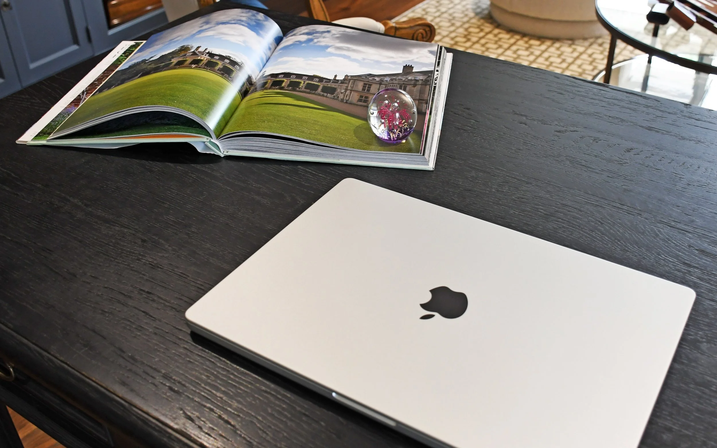Interior view of Cloudview black desk with silver Apple laptop and an open book