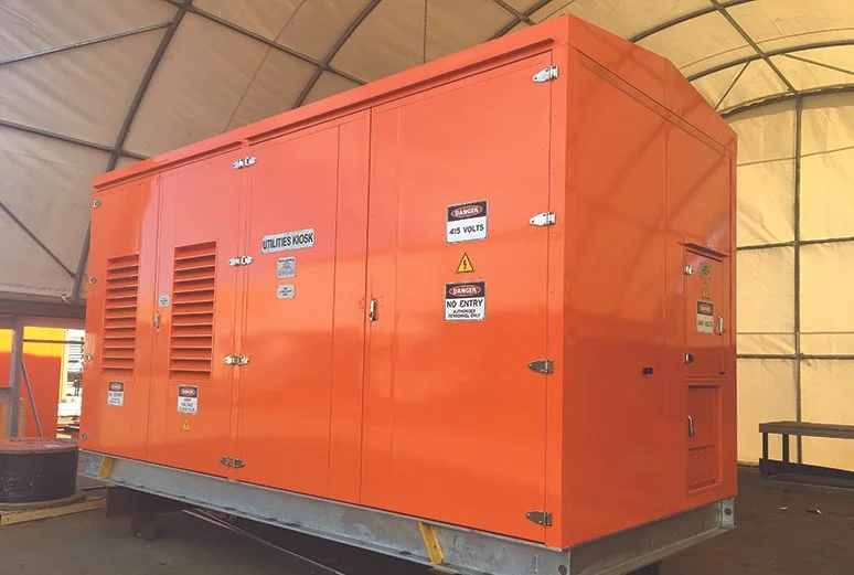 Large orange industrial generator inside a temporary shelter