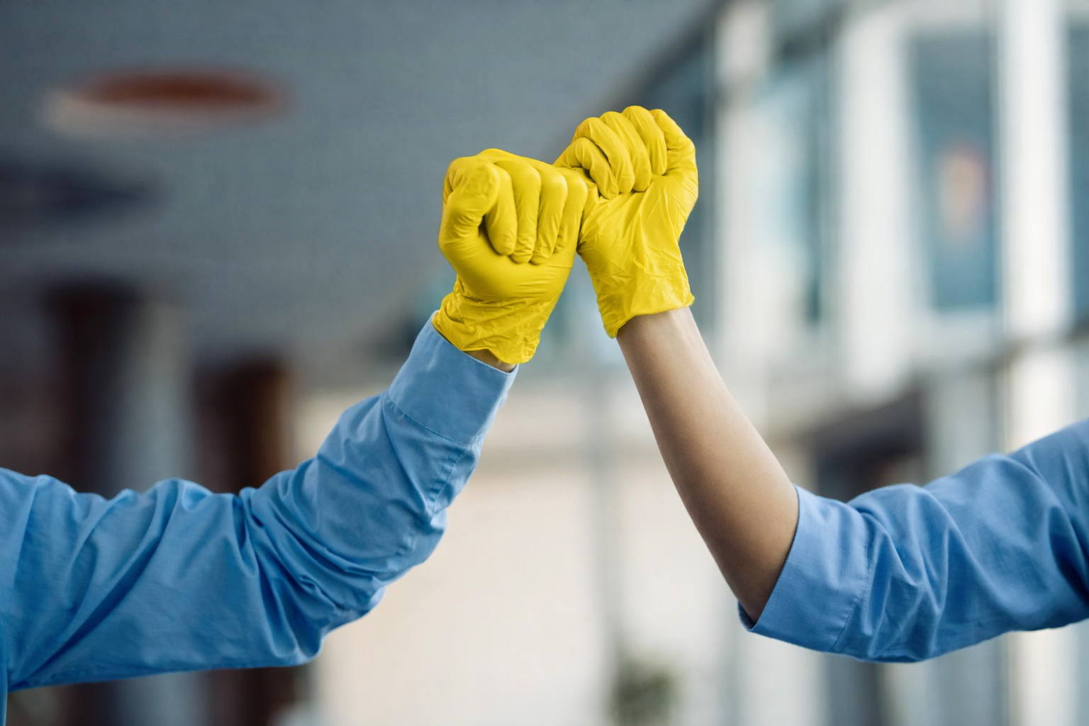 Zwei Hände mit gelben Handschuhen klatschen ein