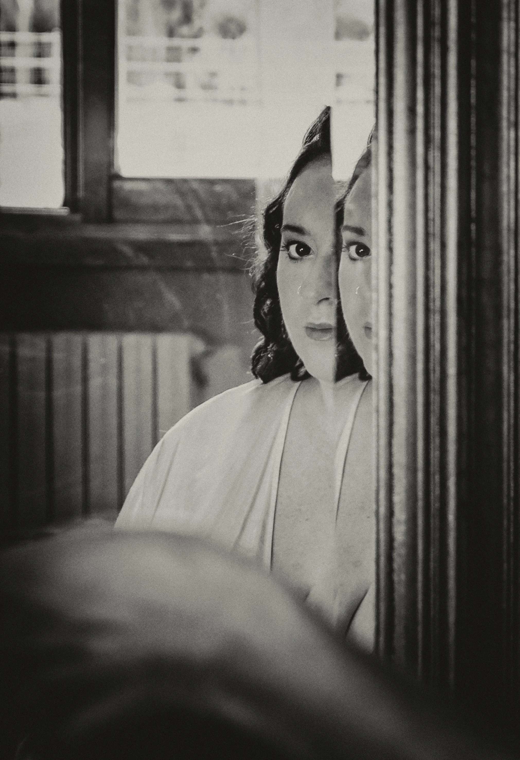 Donna riflessa in uno specchio con effetto artistico in bianco e nero.