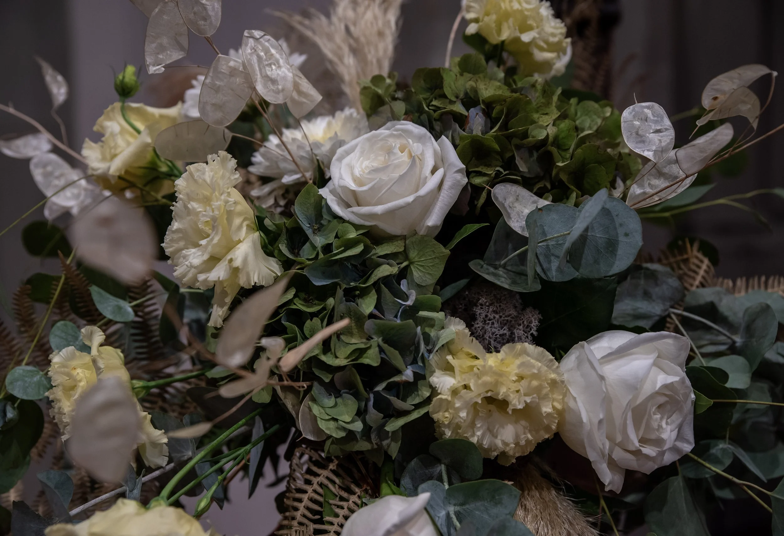 Bouquet floreale con rose bianche, fiori color crema, foglie verdi e elementi secchi.