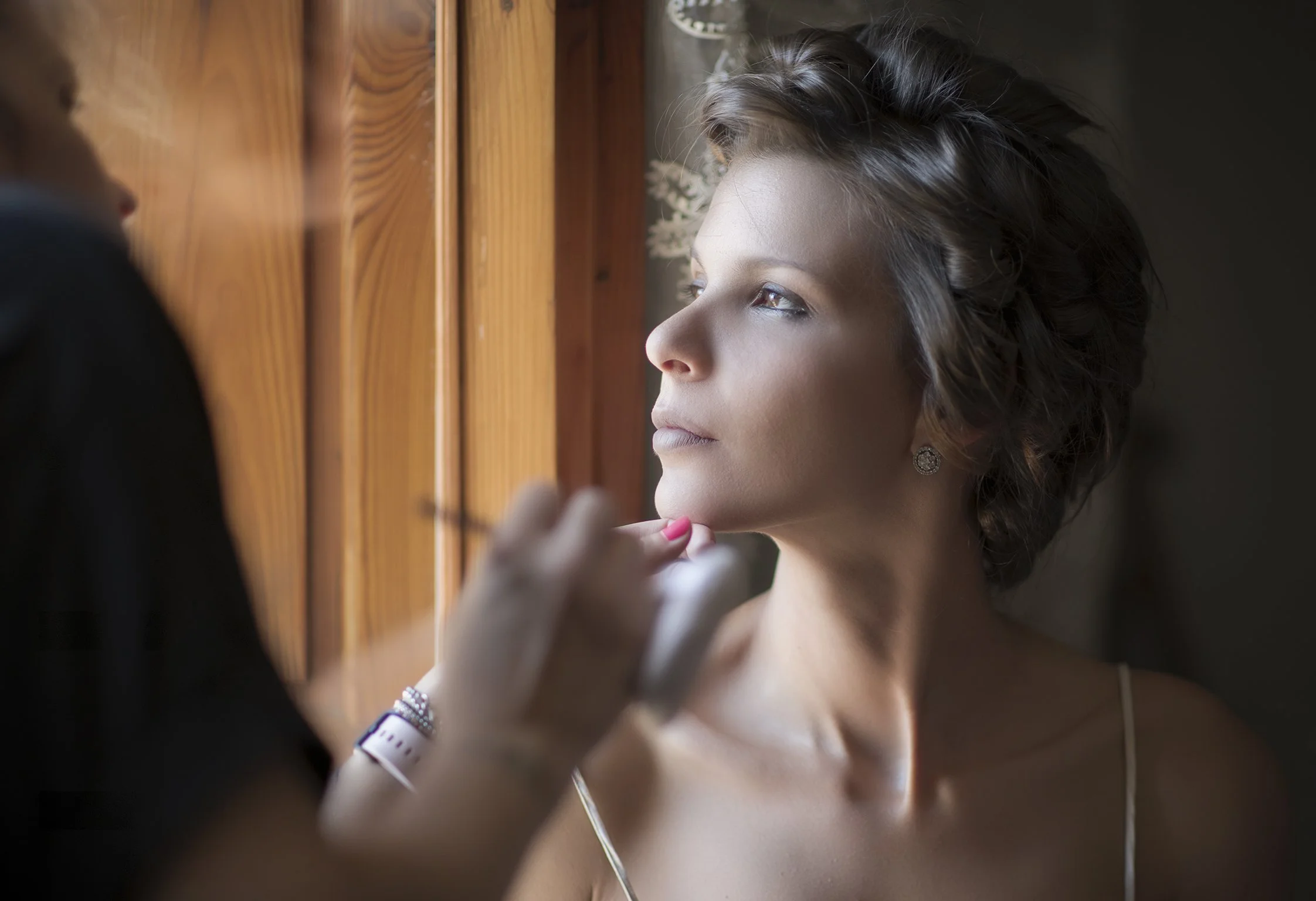 Donna che riceve il trucco vicino a una finestra.