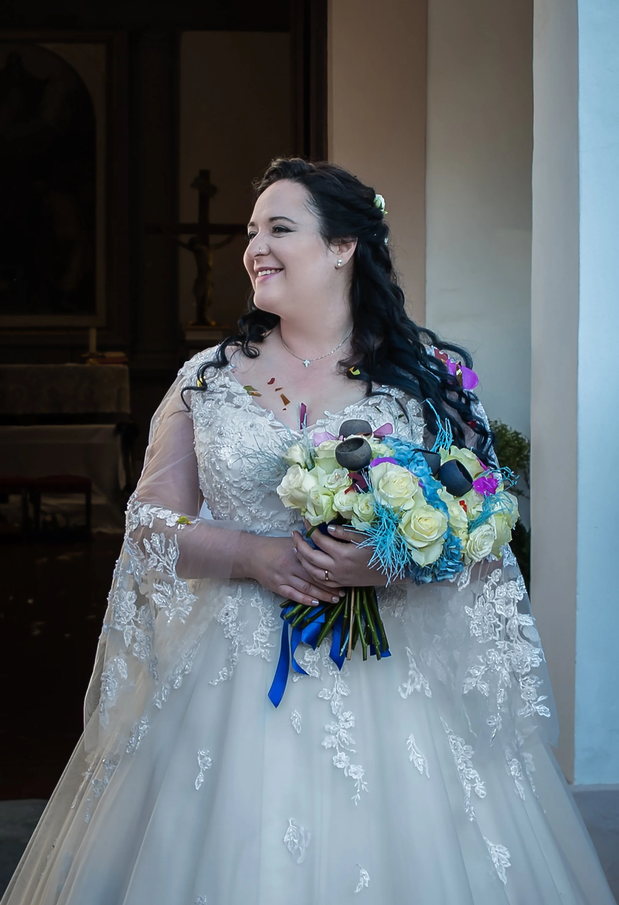 Sposa in abito bianco con bouquet colorato in mano.