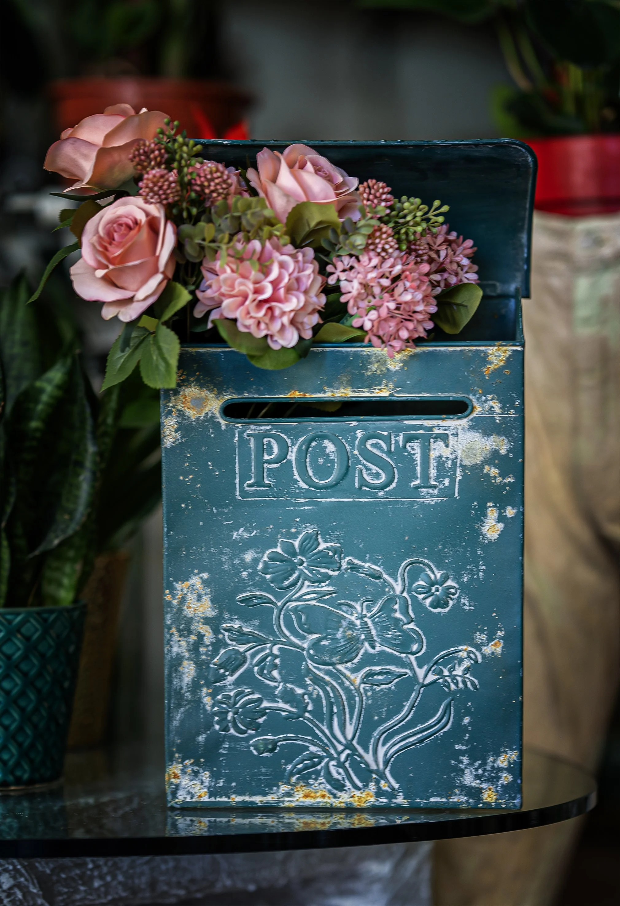 Cassettina postale verde con fiori finti rosa e decorazioni floreali in rilievo sulla superficie.