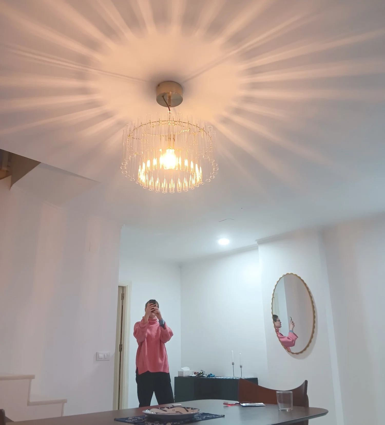 A woman taking a photo of a chandelier illuminating a living room