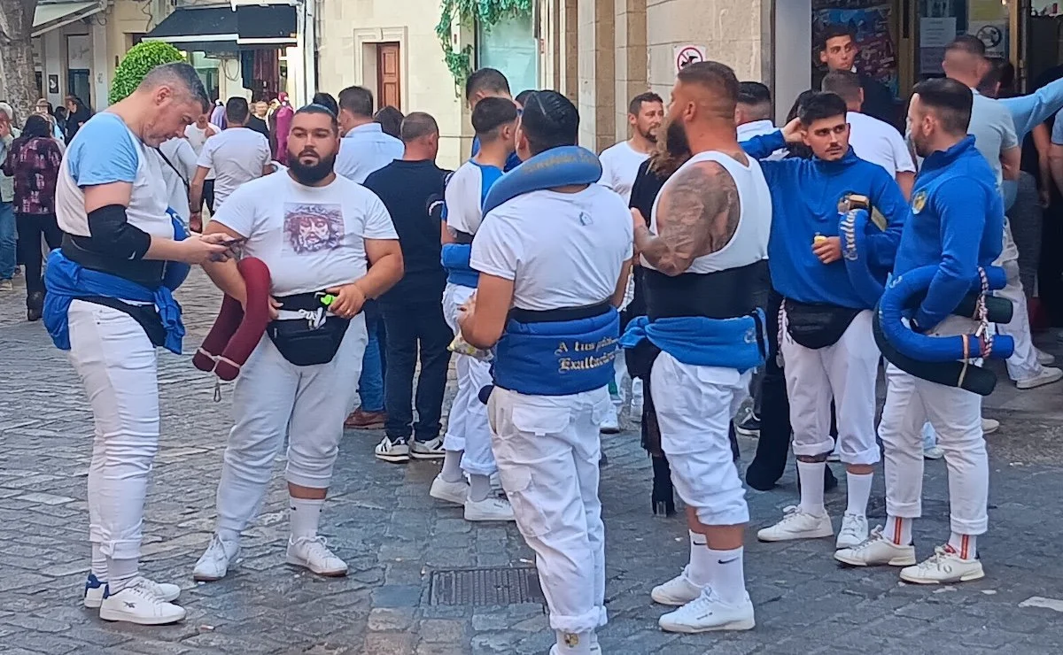 A group of strong looking men having a snack outside a convenience store