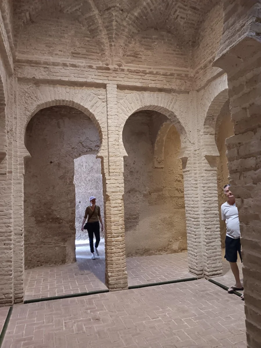 Two people standing in an ancient stone room at the Alcázar of Jerez