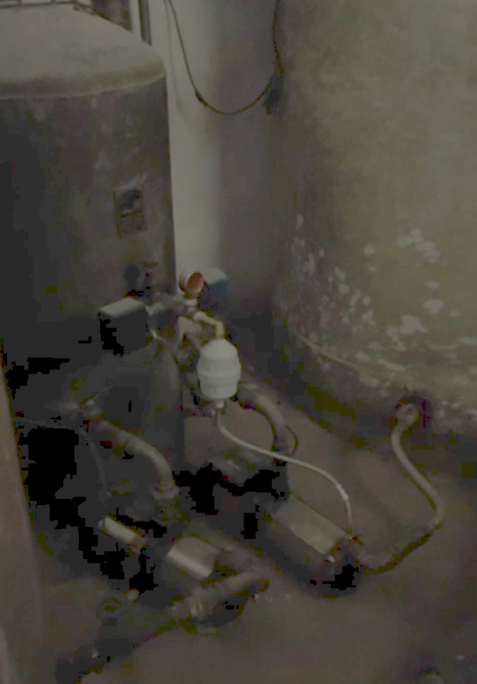 A water tank and pump in the basement of an apartment building