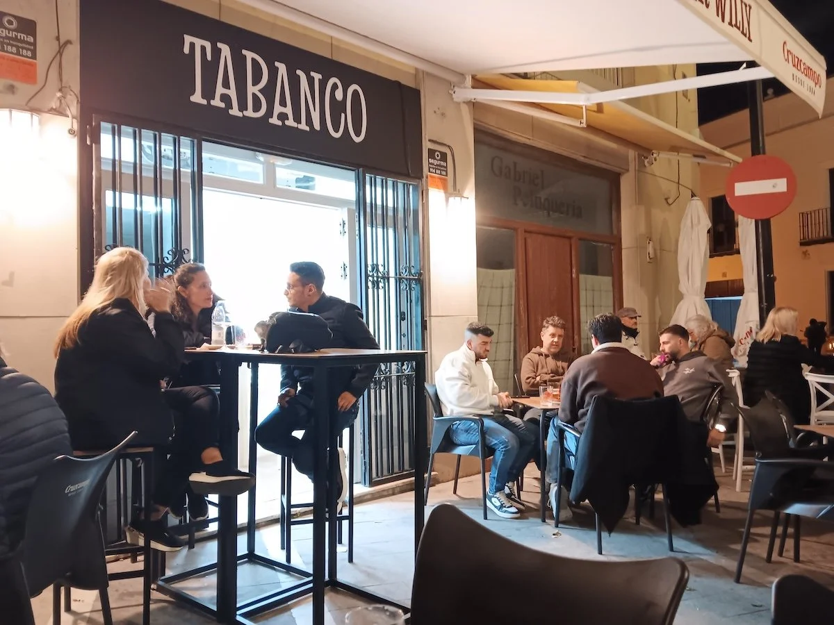 People sitting at outdoor tables at a bar