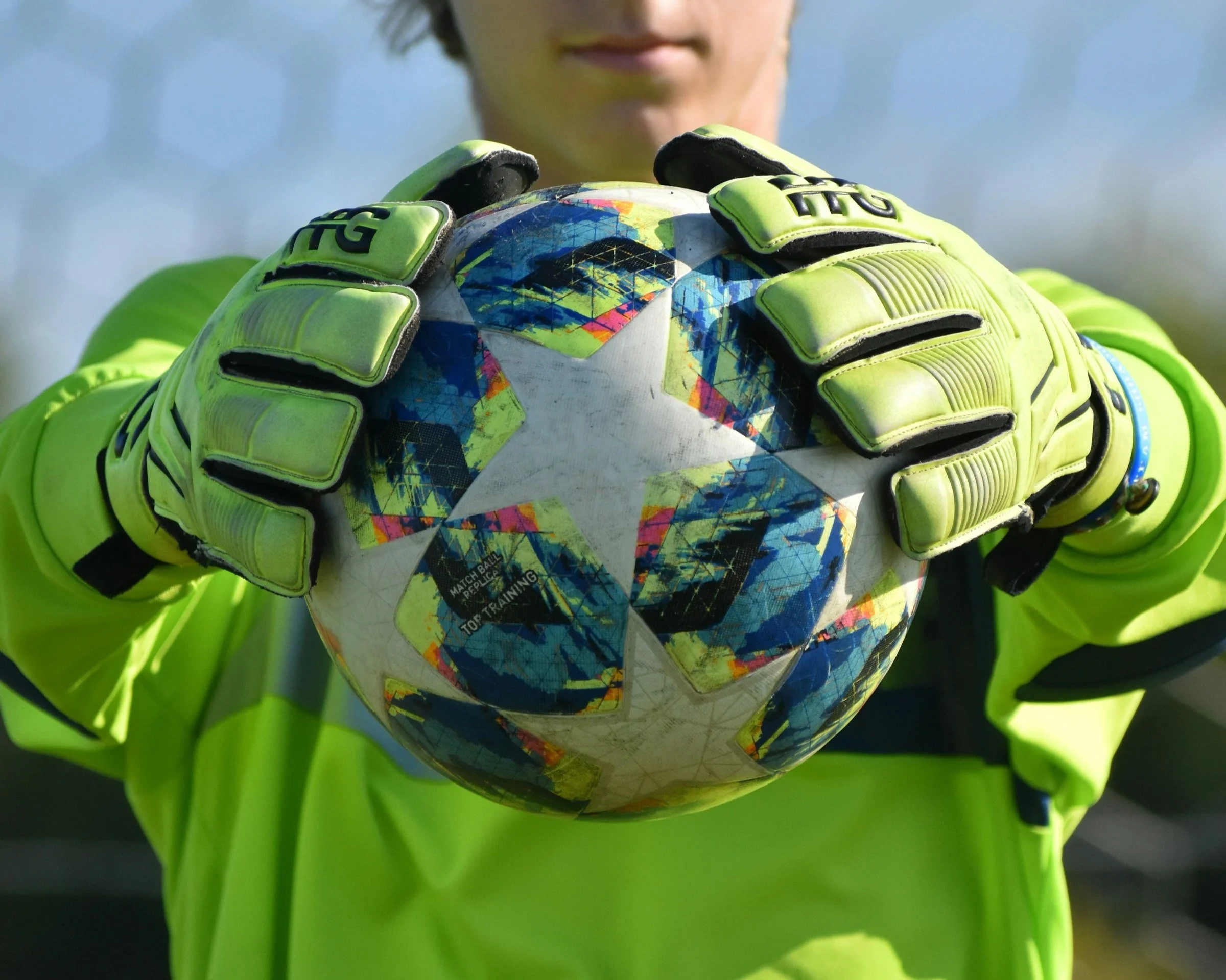 Torwart hält Fußball mit Handschuhen im Bereich des Tors.