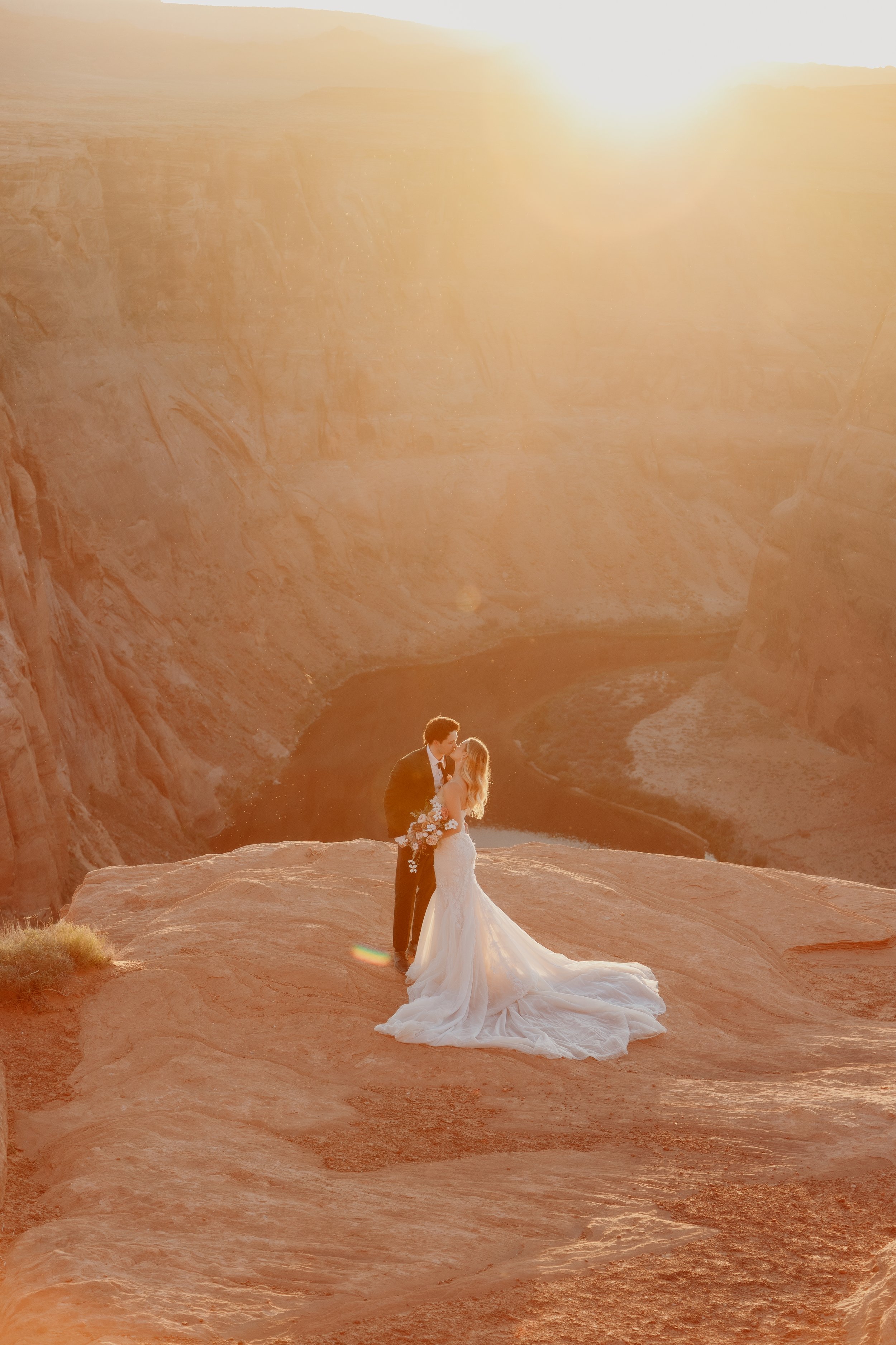 Bride and groom kissing at Horseshoe Canyon during golden hour, romantic wedding photography.