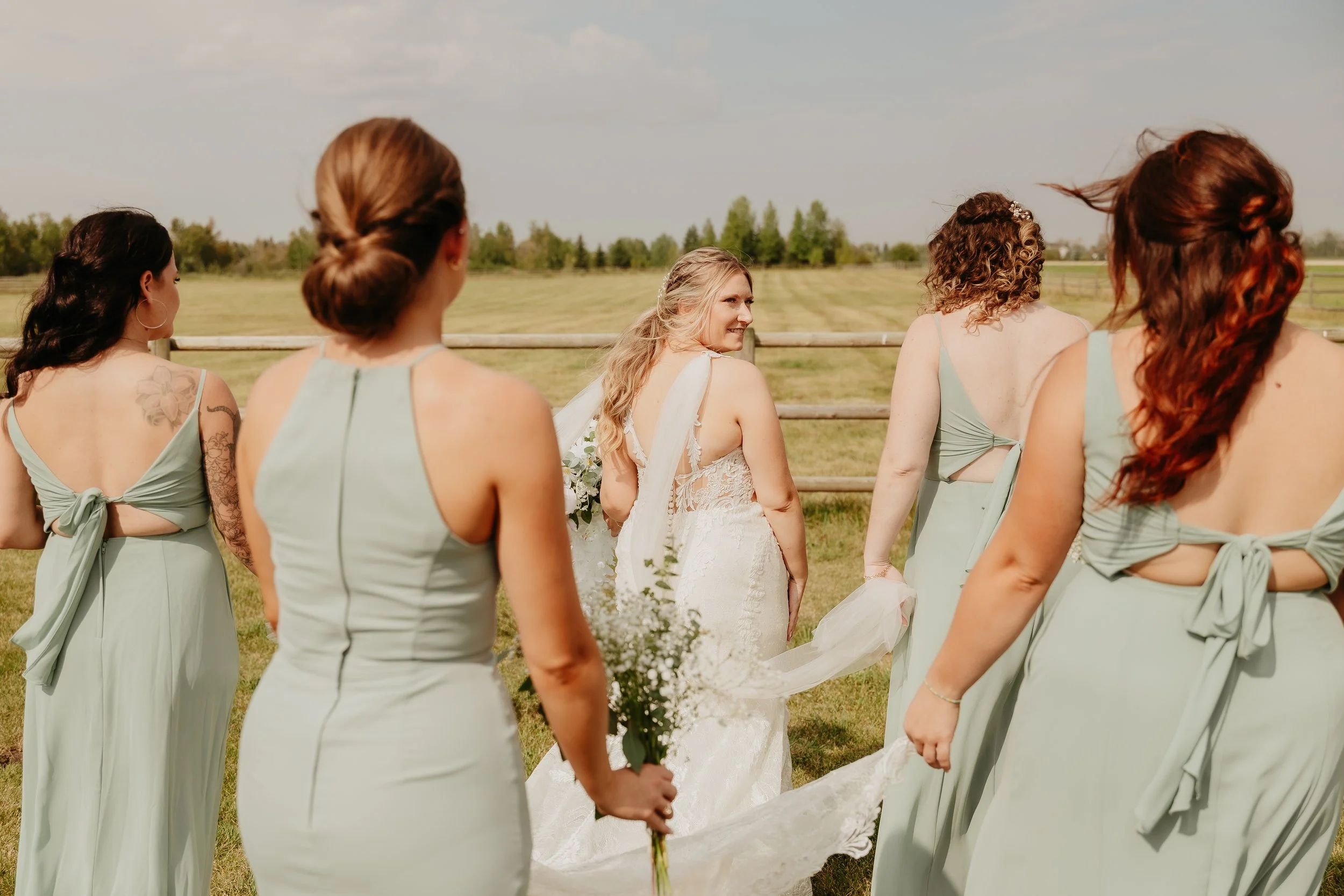 Candid bridal portrait of the bride glancing back at her bridesmaids after getting ready.