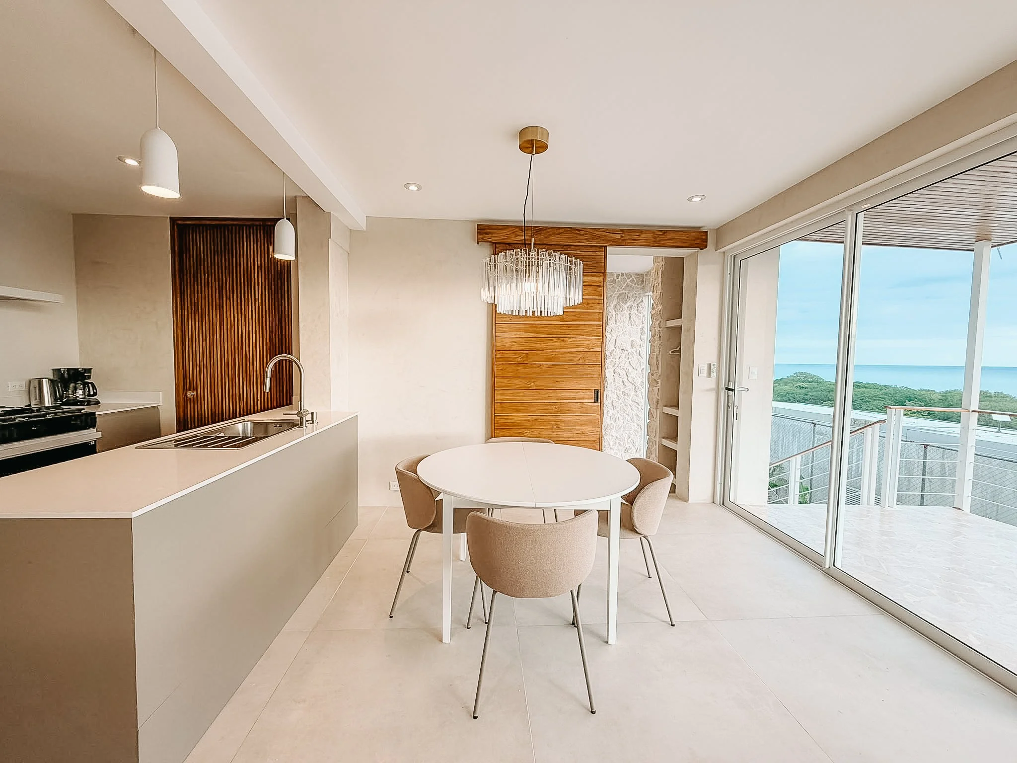 Dining area and fully equipped kitchen at Casa Cueva with sliding doors opening to the ocean-view terrace.