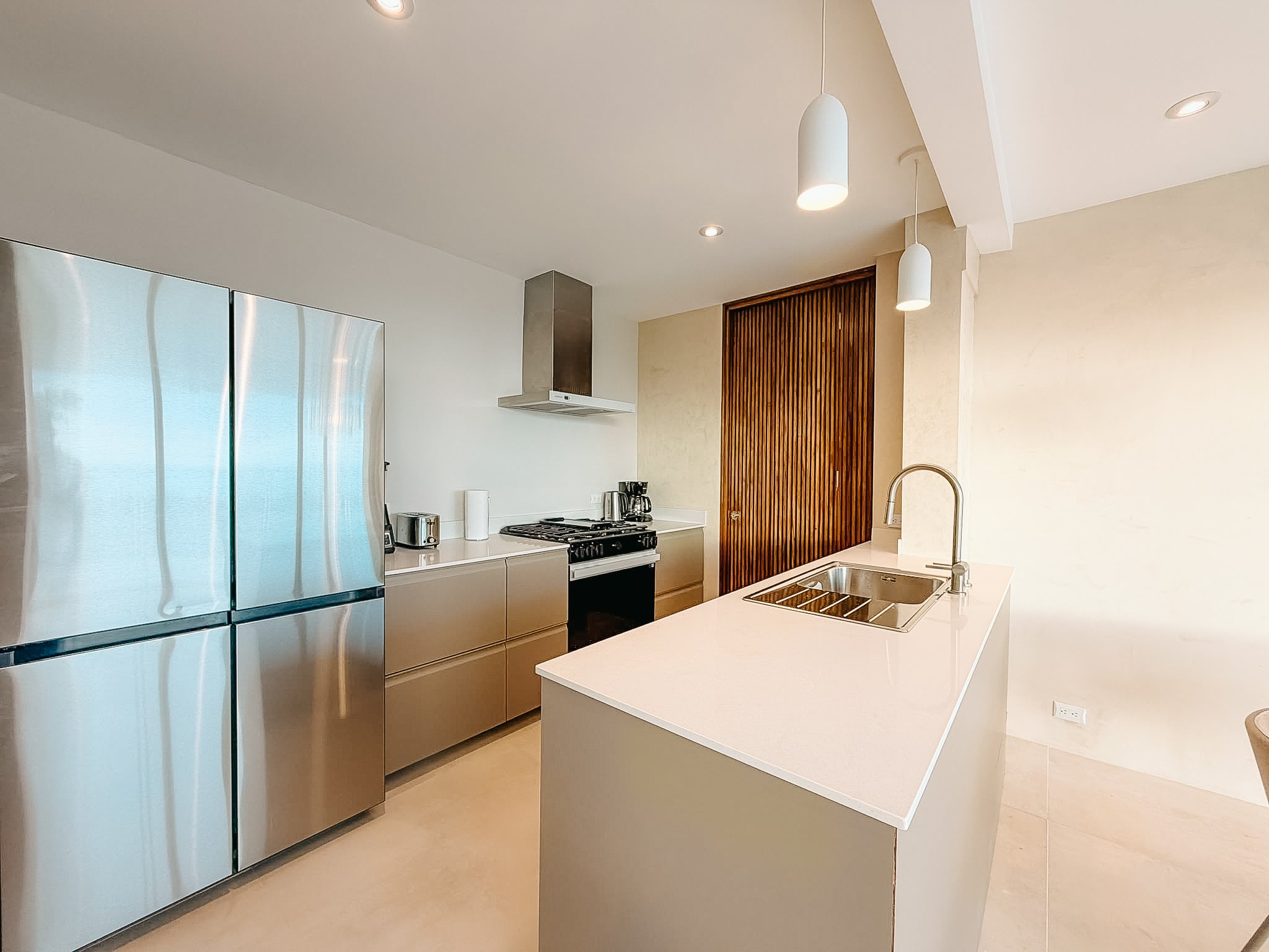 Fully equipped Casa Cueva kitchen with island, gas stove, large refrigerator and warm natural wood details.