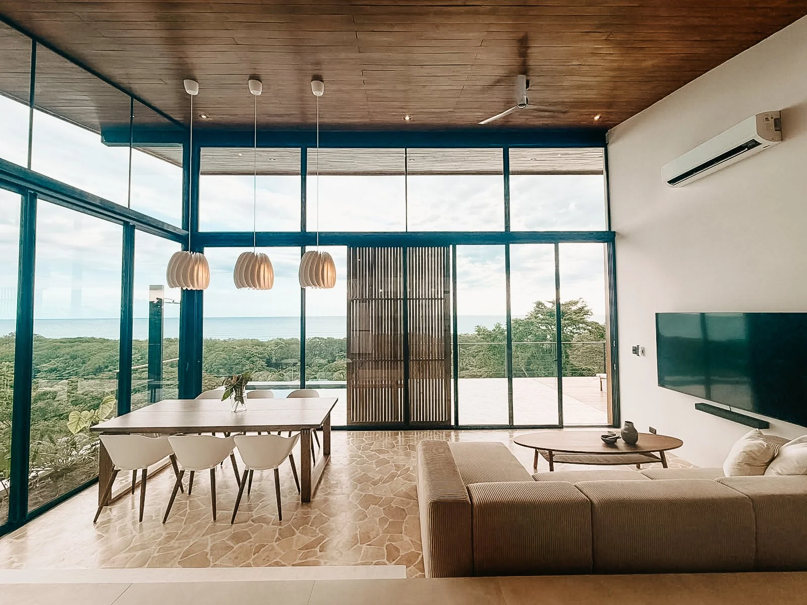 Open-plan living and dining area at Villa Nalu with floor-to-ceiling windows and ocean views in Santa Teresa, Costa Rica