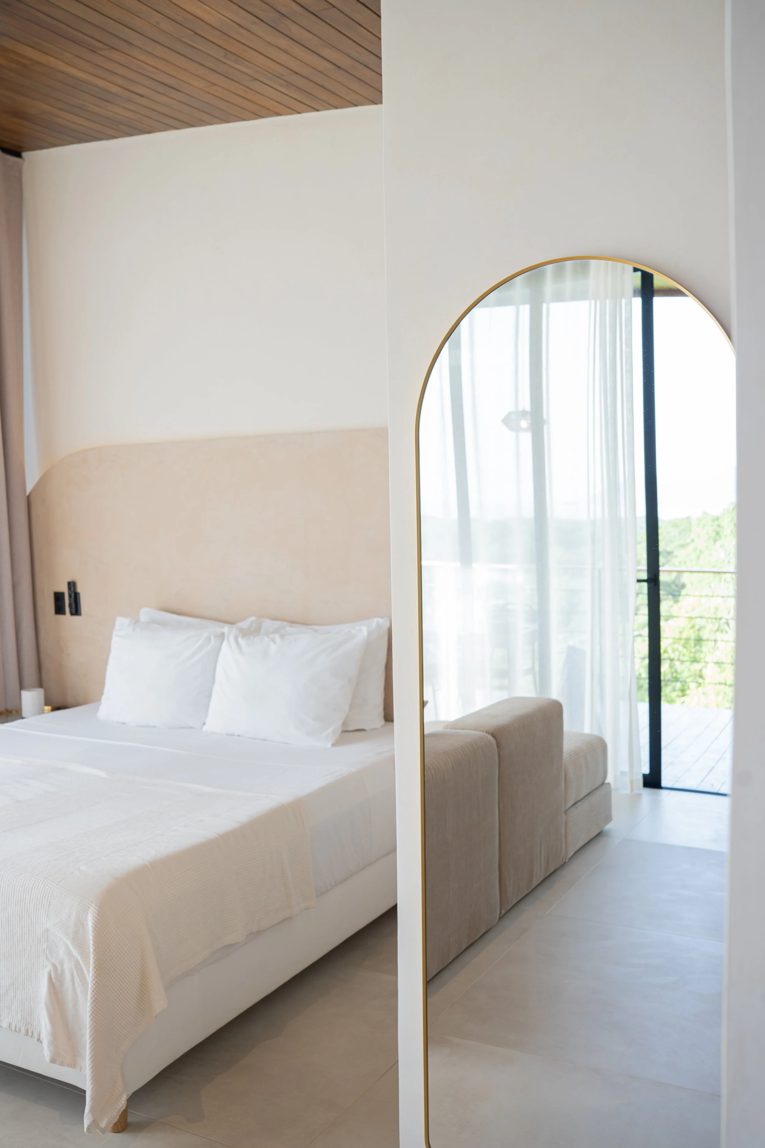 Casa Surya boutique studio with king-size bed, arched mirror and ocean-view terrace reflected in the mirror.