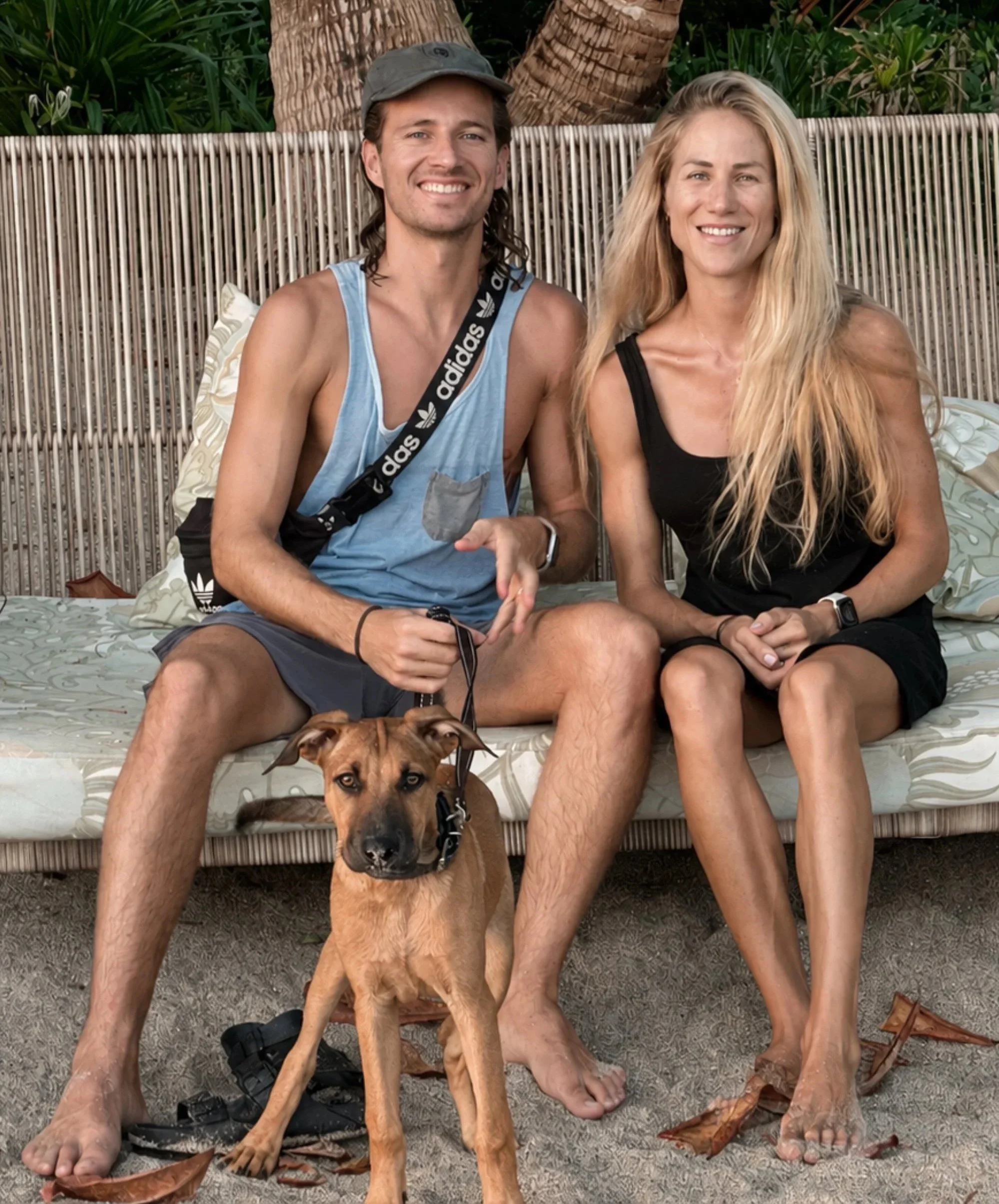 A smiling couple seated with their dog Nalu in Santa Teresa, Costa Rica.