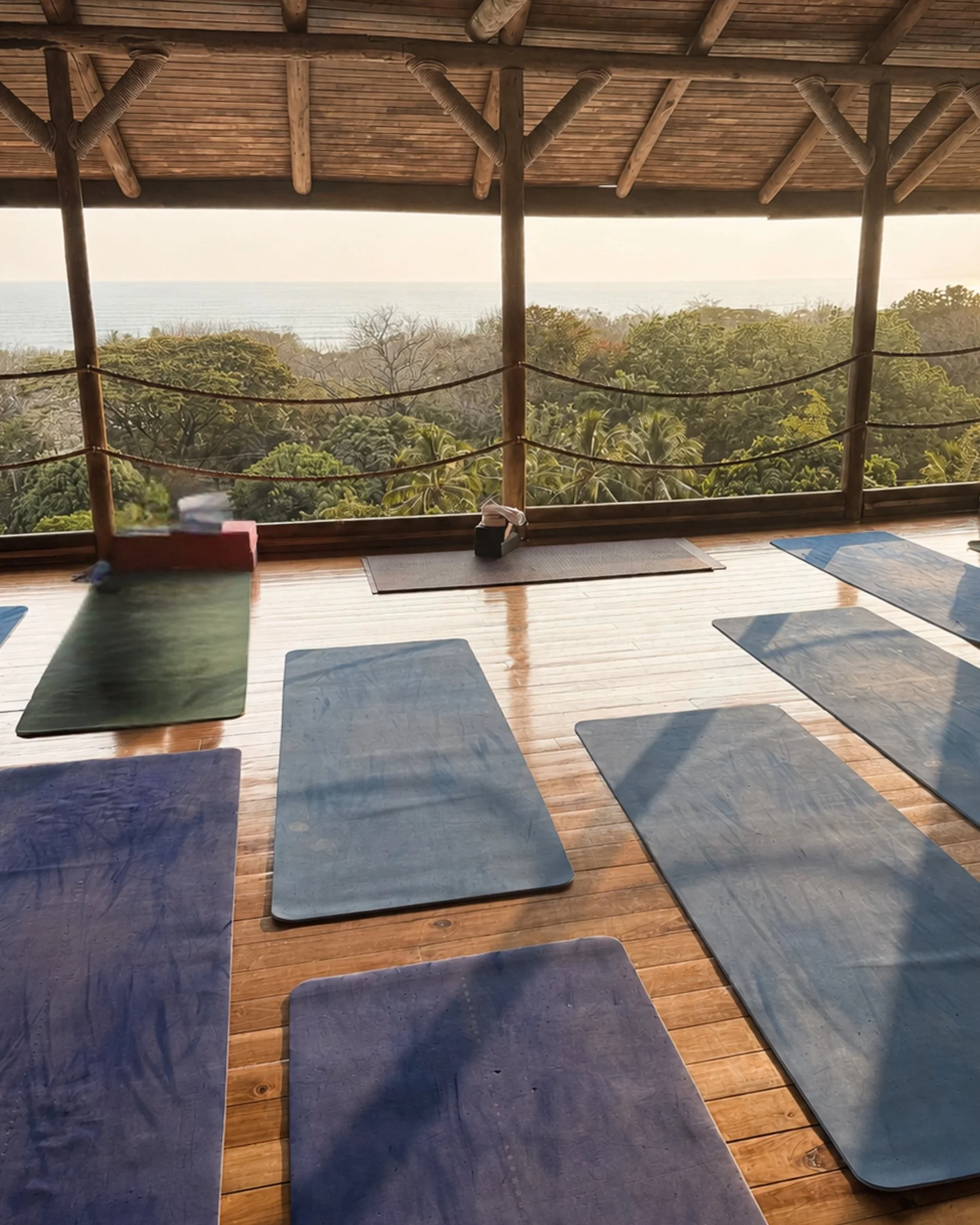 Yoga practice on an open wooden deck overlooking the Pacific Ocean.