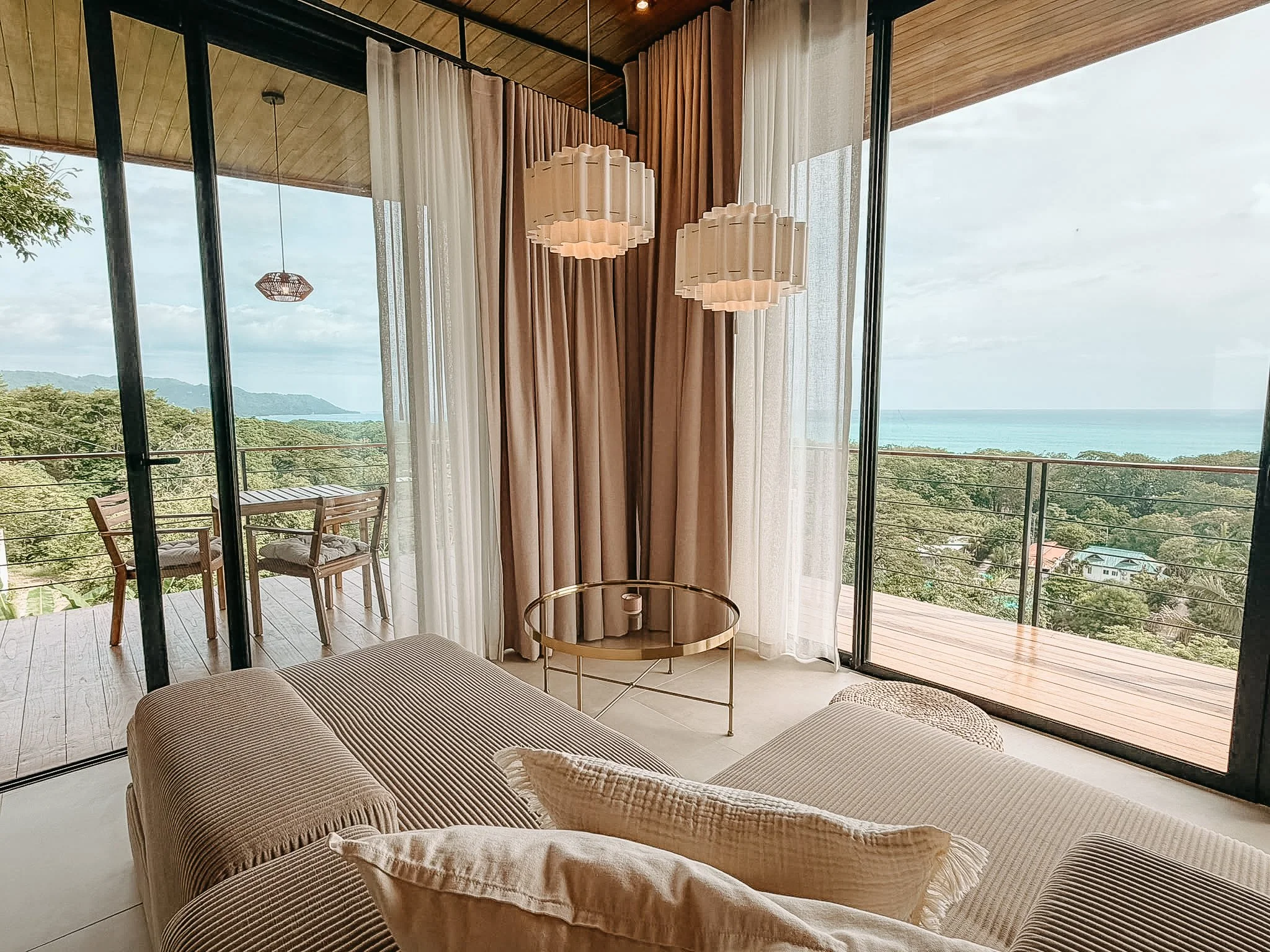 Relaxing lounge area at Casa Surya with floor-to-ceiling windows, a private terrace and ocean views in Santa Teresa, Costa Rica.