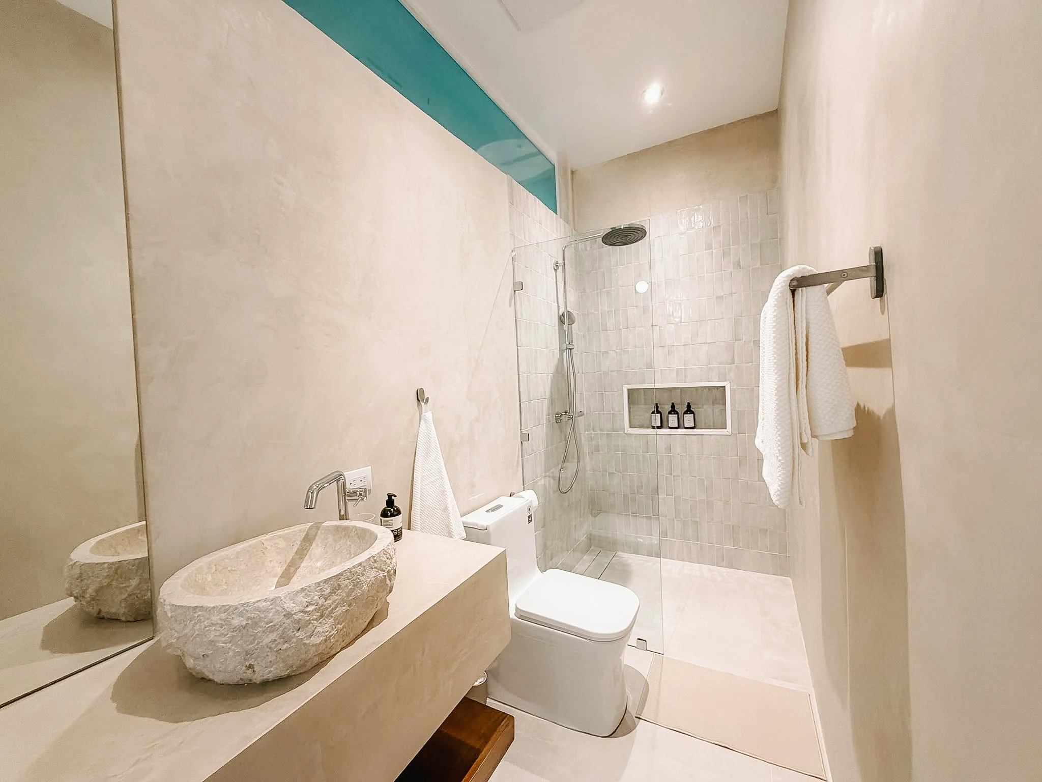 Casa Cueva bathroom with a natural stone basin, walk-in rain shower and warm neutral finishes.