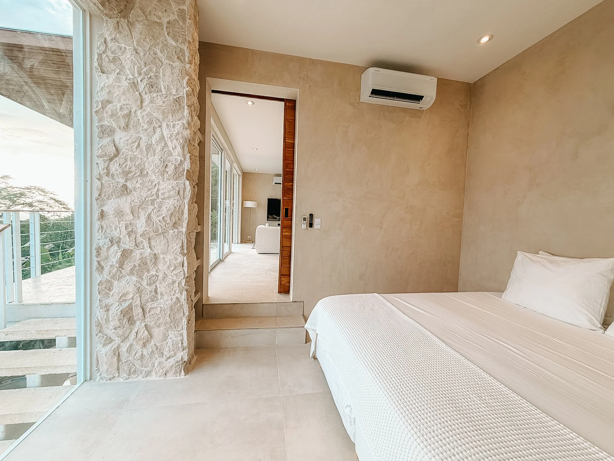 Second bedroom at Casa Cueva with a European king bed, natural stone wall, air conditioning and access to the living area.