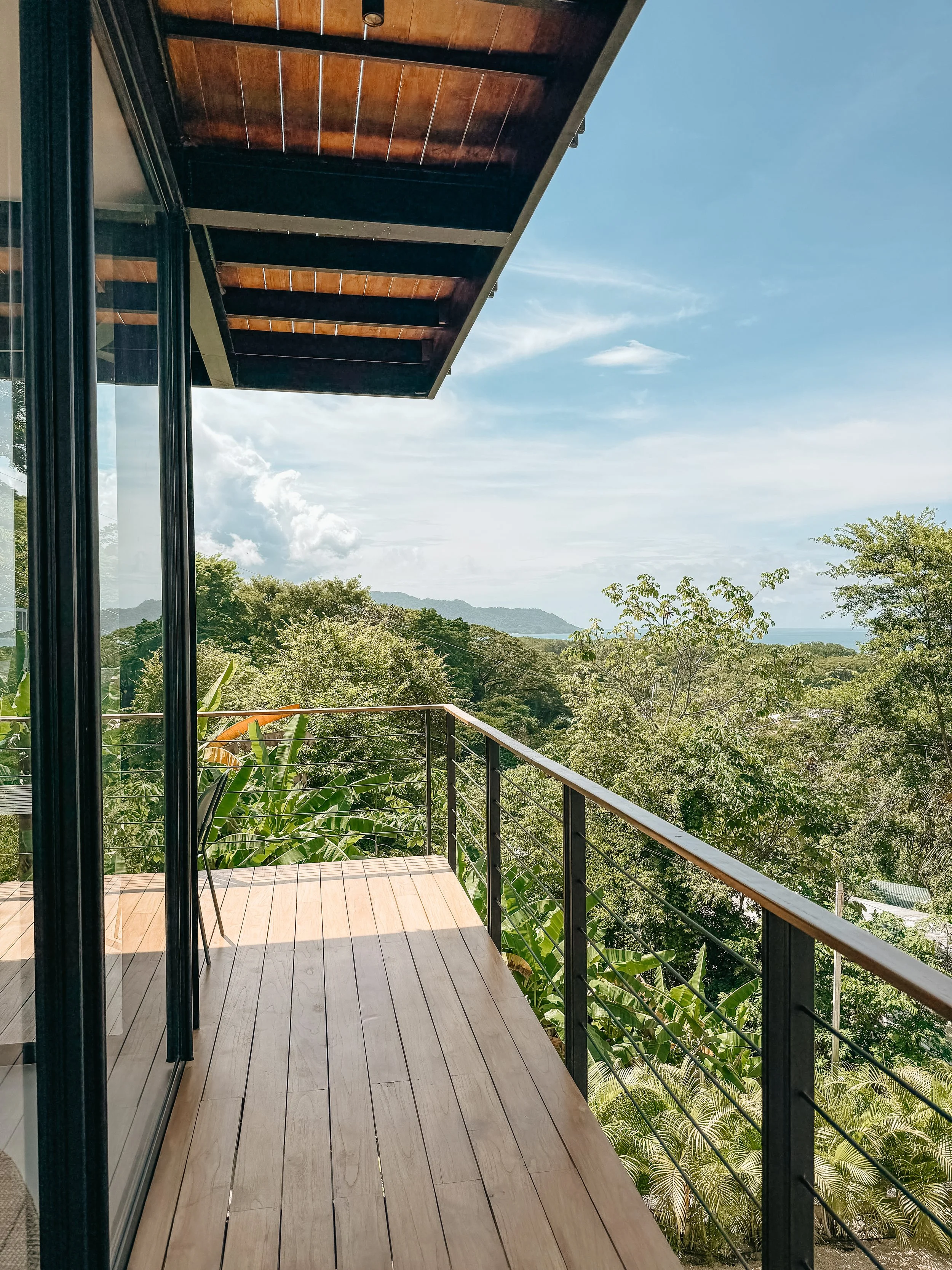 Covered terrace lounge overlooking the treetops toward the Pacific.