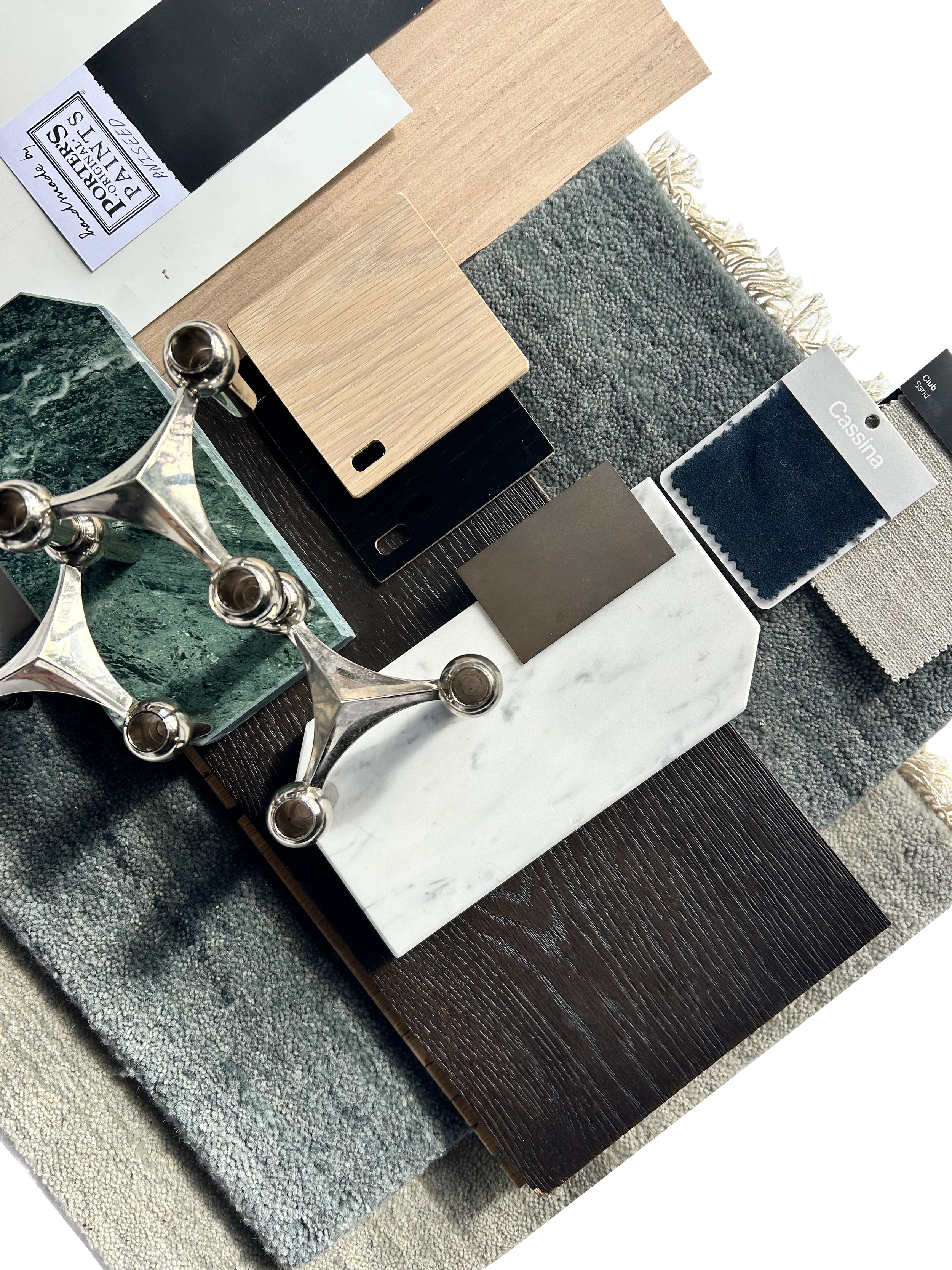 A selection of interior design materials and samples arranged on a table, including fabric swatches, wood and tile samples, and a decorative metallic piece.
