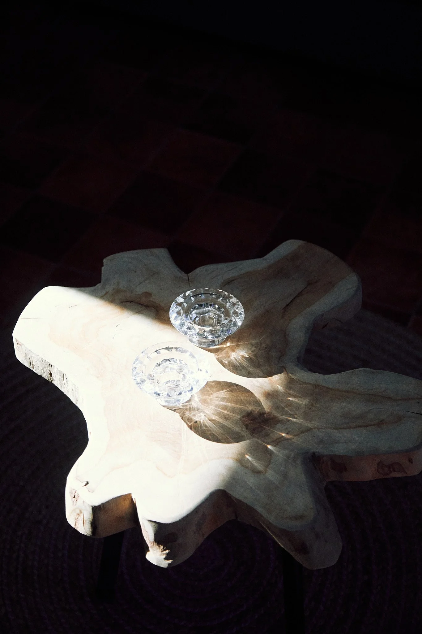 Rustic wooden table with two crystal candle holders casting shadows