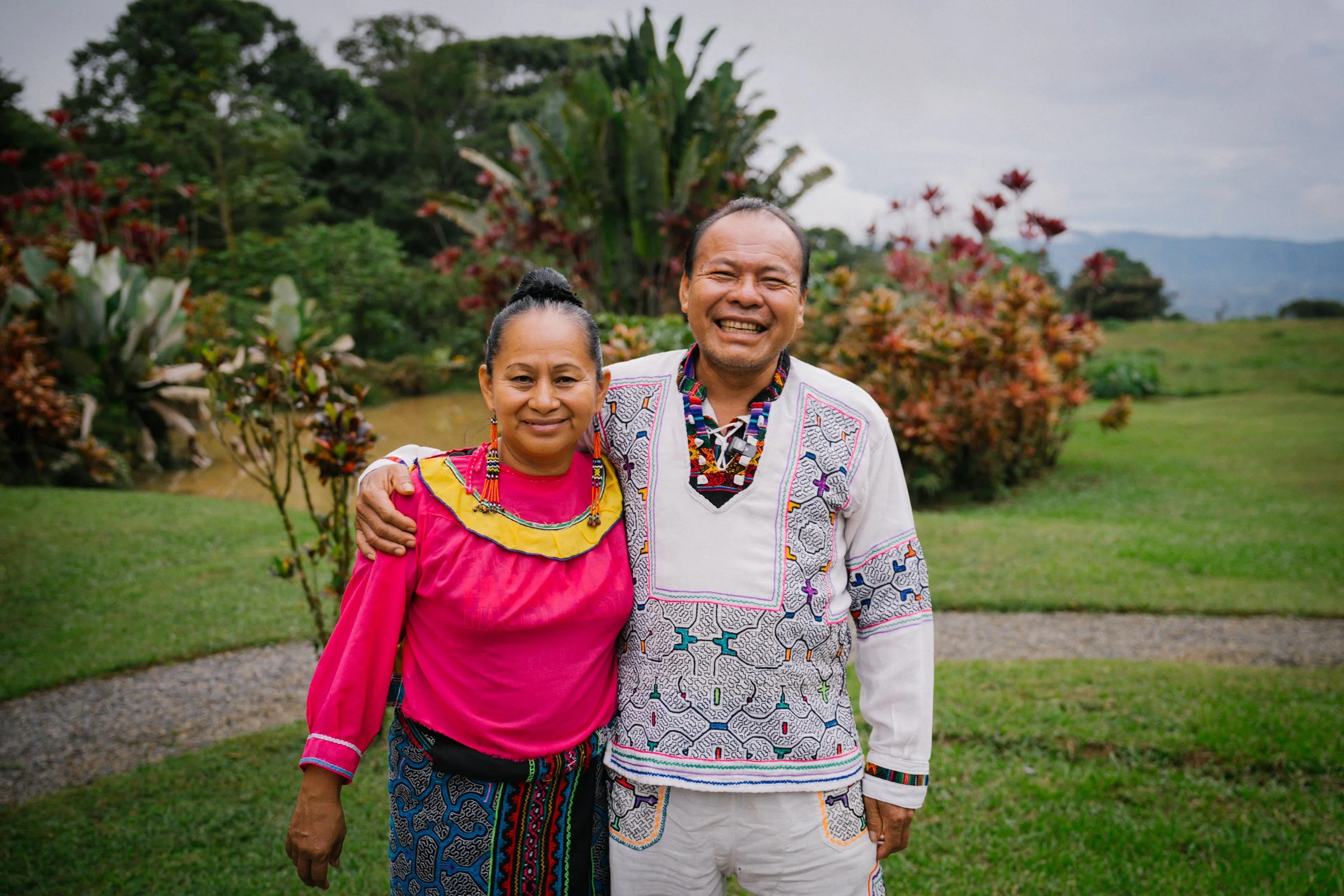 Two people examining colorful, intricately patterned textile art and beadwork.