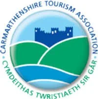 Logo of the Carmarthenshire Tourism Association featuring a castle, green hills, and a river.
