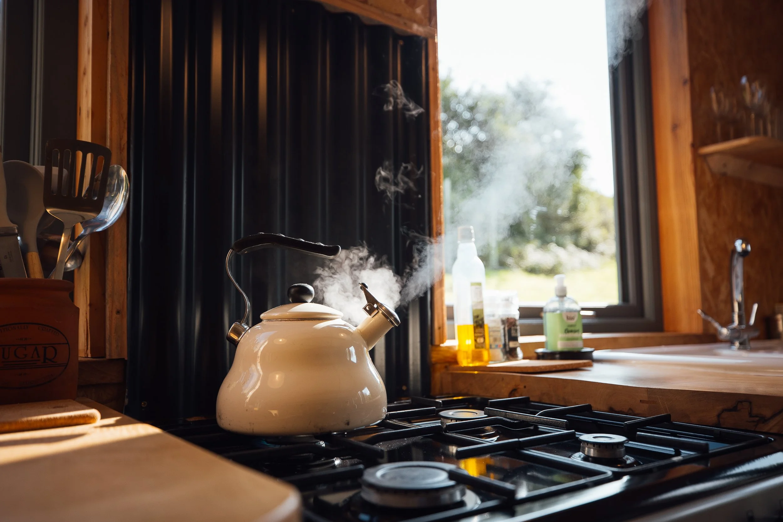 Kettle boiling on hob at Ty Mawr, steam billowing up lit by sunlight coming in through the window.