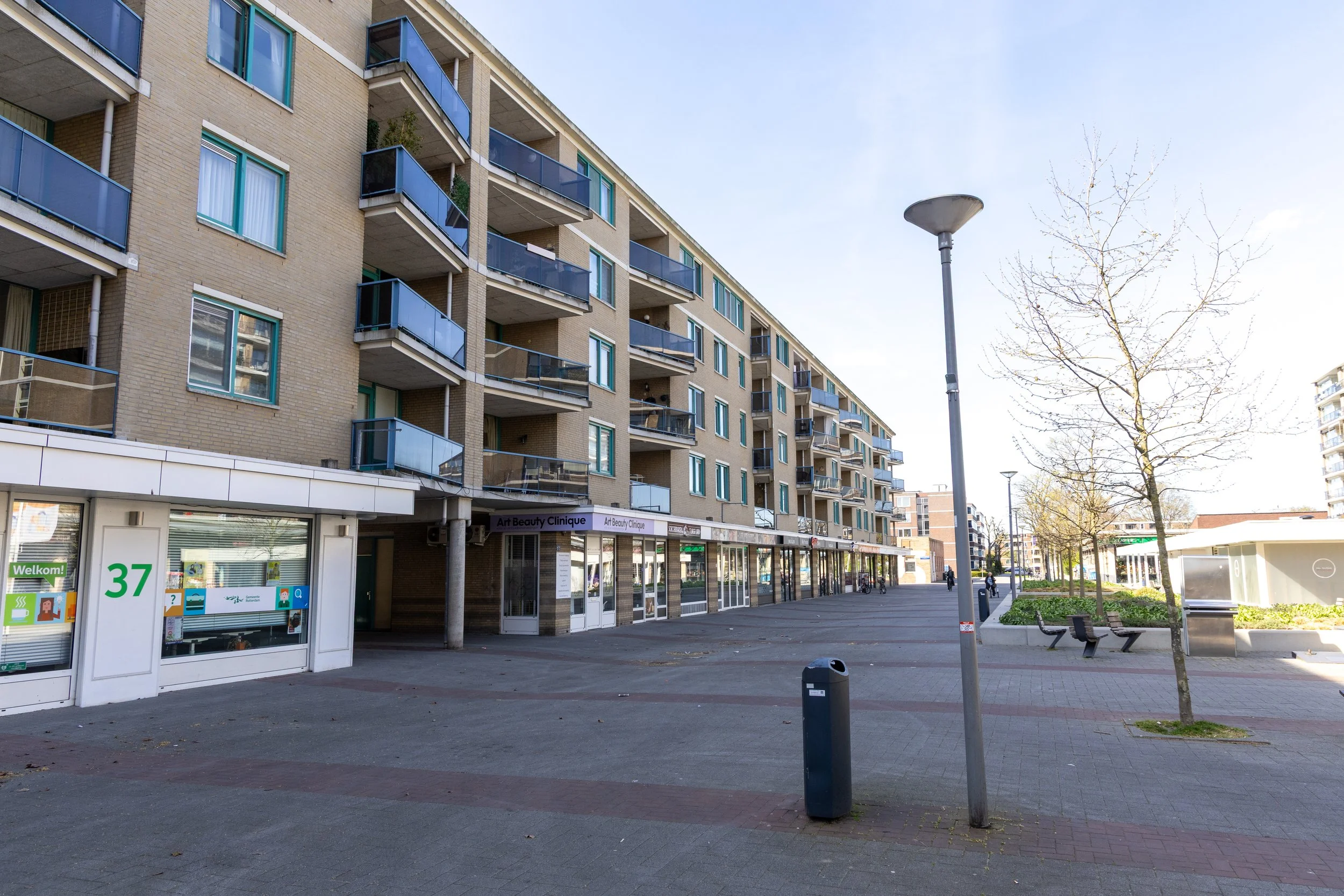 Woonproject Van Milplaats — gevel met balkons en winkels op de begane grond