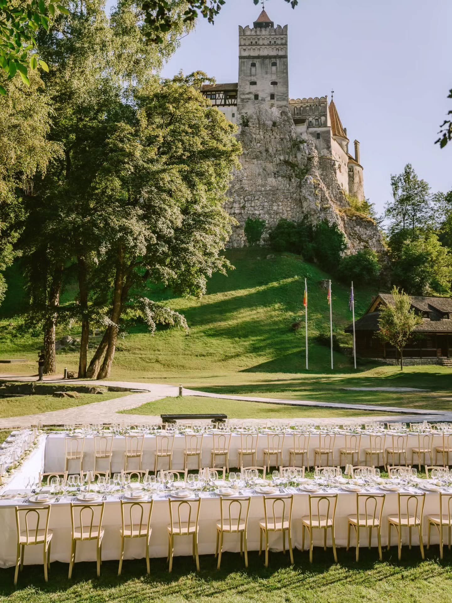 Dinner beneath Bran Castle (aka Dracula's castle), with a horseshoe tablescape designed to match this jaw dropping setting. Candlelit tables layered with white roses, eucalyptus and soft table lamps, with gothic menus grounding the look in its surrou