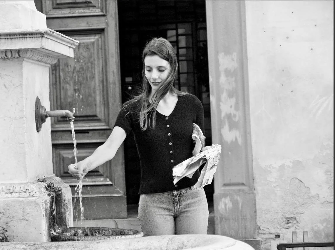 Fotografia fine art em preto e branco de mulher junto a uma fonte — obra de Alexandre Horta e Silva que revela o cotidiano com leveza e introspecção.
