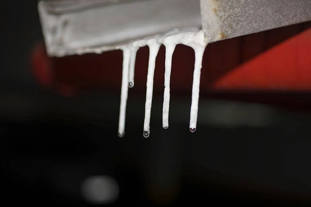 Fotografia fine art de goteiras congeladas pendendo de uma superfície metálica — obra minimalista de Alexandre Horta e Silva sobre tempo e matéria.