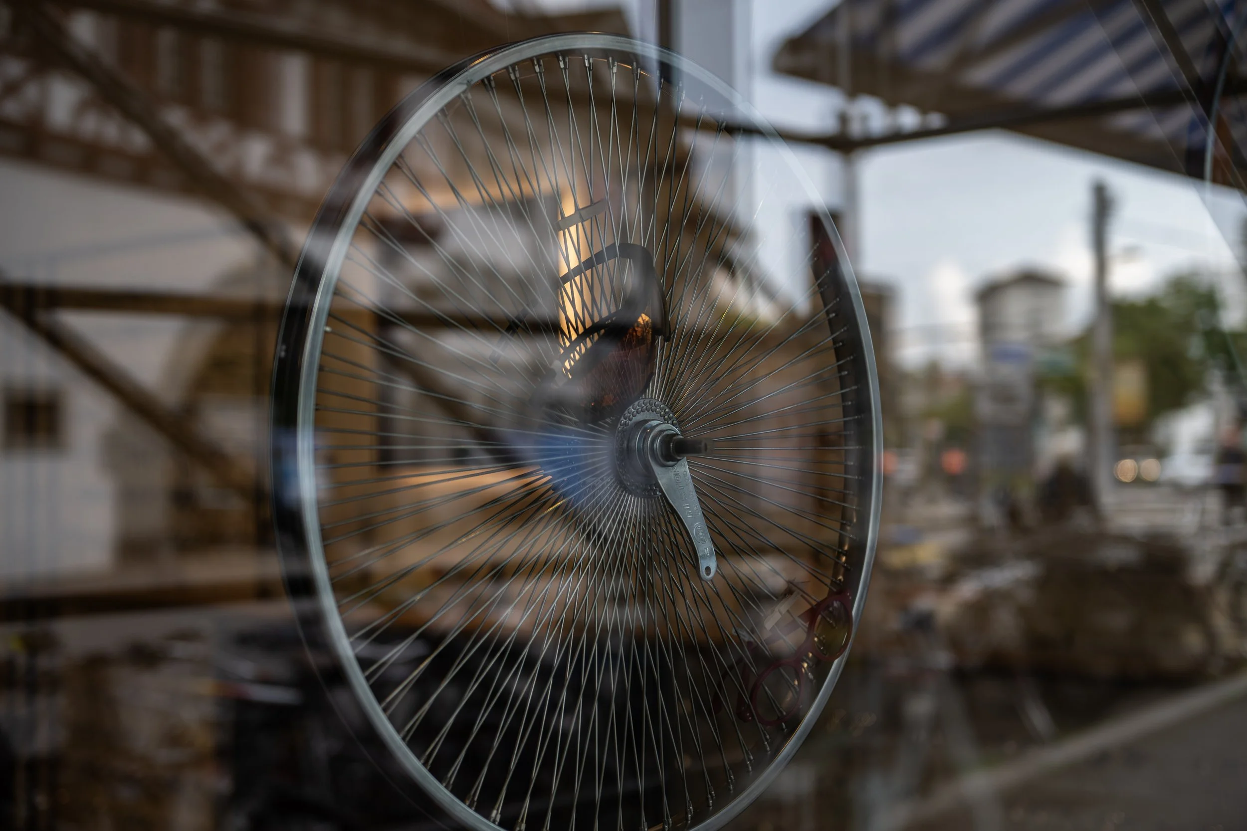 Fotografia fine art mostrando o reflexo de uma roda de bicicleta em uma vitrine urbana — obra de Alexandre Horta e Silva que explora movimento e transparência na paisagem contemporânea.