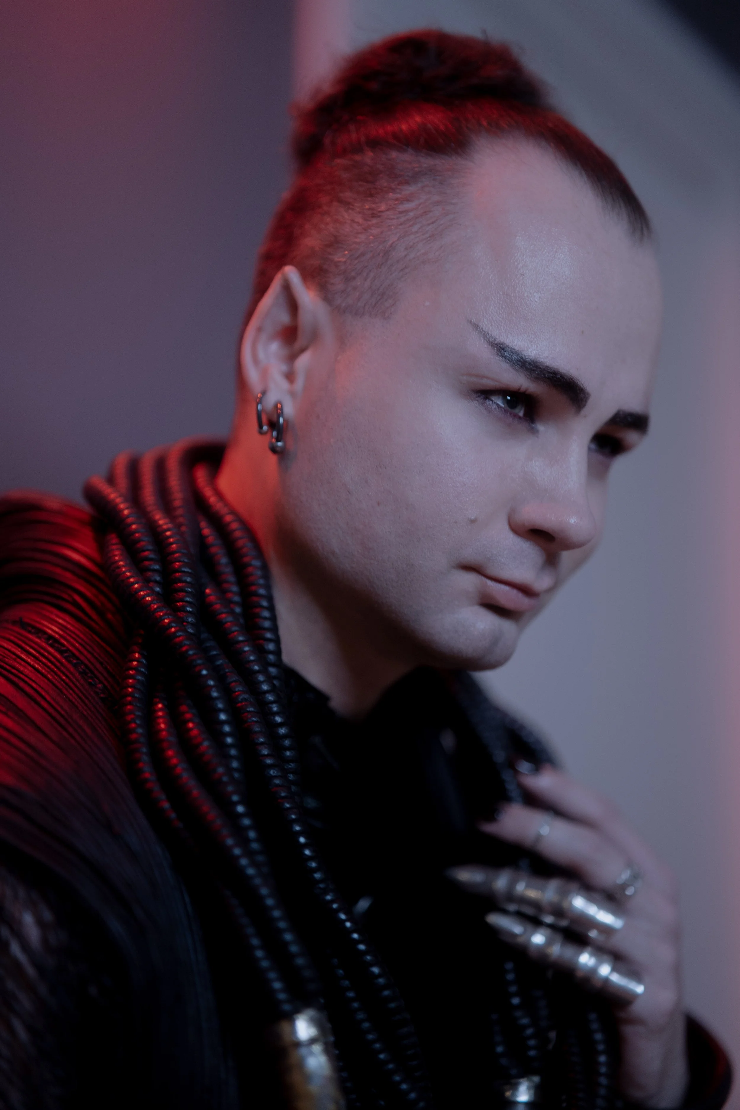 Close-up of a Dominant with multiple earrings and pointed ears