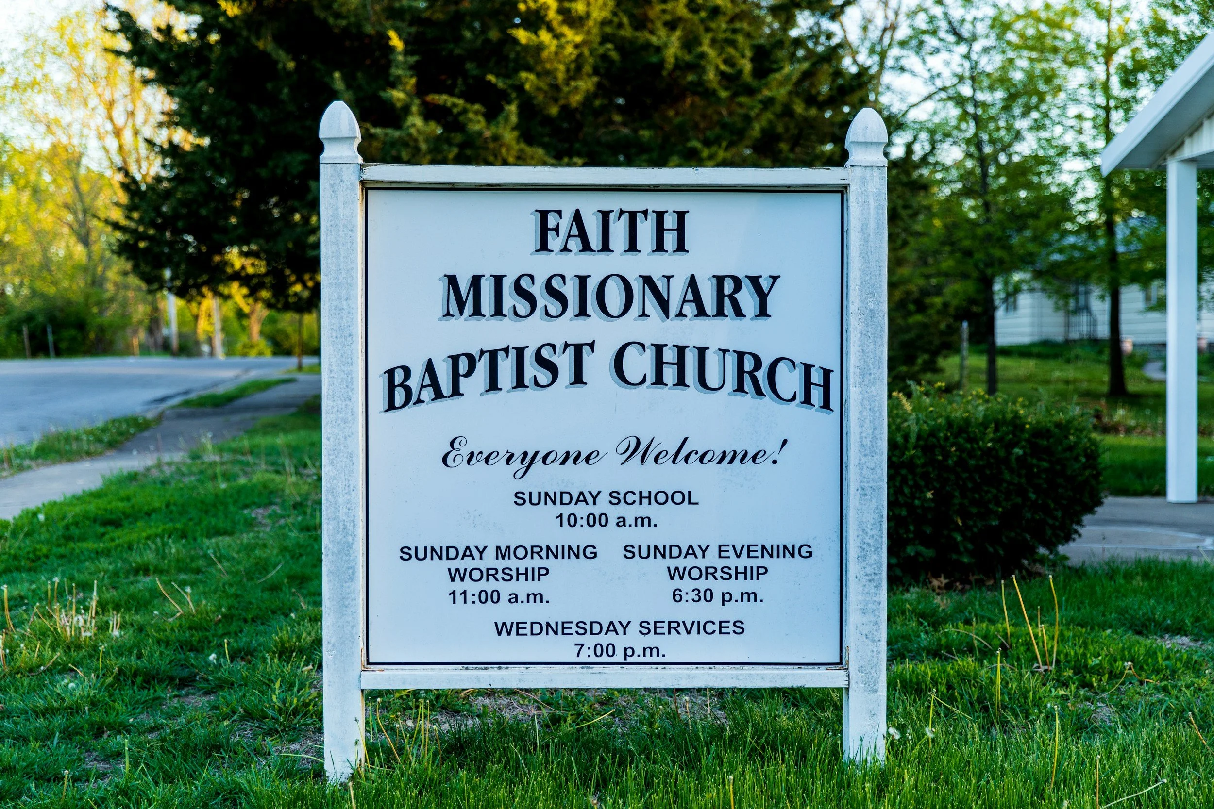 Sign outside Faith Missionary Baptist Church listing service times for Sunday school, morning and evening worship, and Wednesday services.