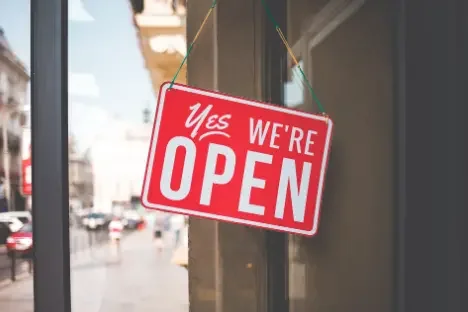 Red and white sign hanging outside that says 'Yes We're OPEN'.