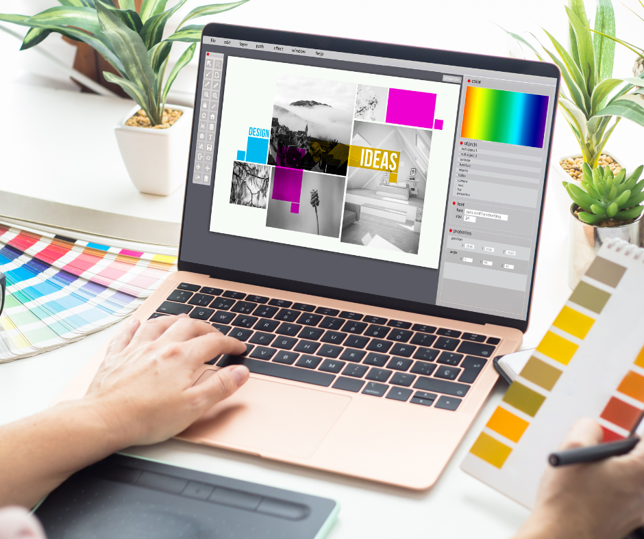 A person working on graphic design software on a laptop, with color swatches, a color palette chart, and potted plants on a white desk.