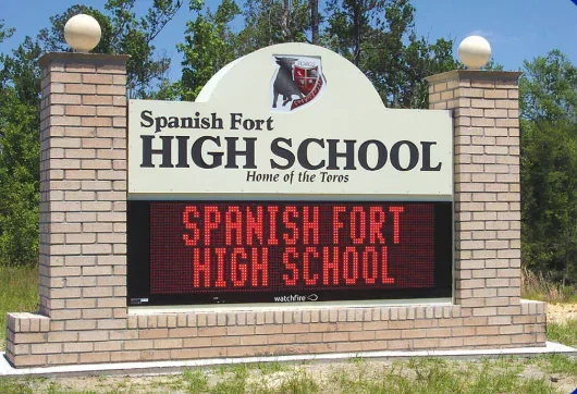 Sign for Spanish Fort High School with a brick base, white background, and digital display reading 'SPANISH FORT HIGH SCHOOL'.
