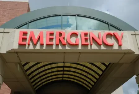 Hospital emergency entrance sign with large red letters on a building exterior.
