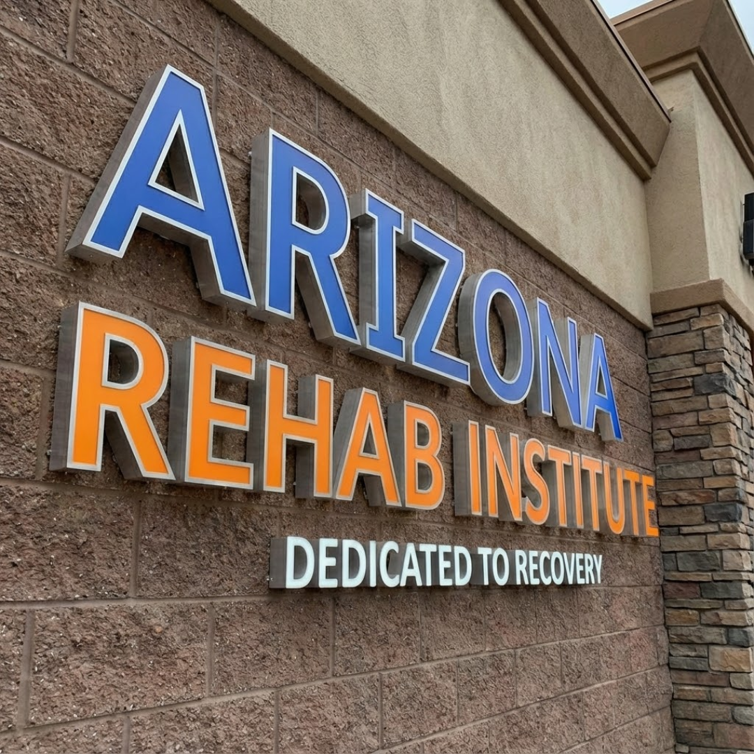 Sign on a brick wall reading 'Arizona Rehab Institute' with the slogan 'Dedicated to Recovery'.