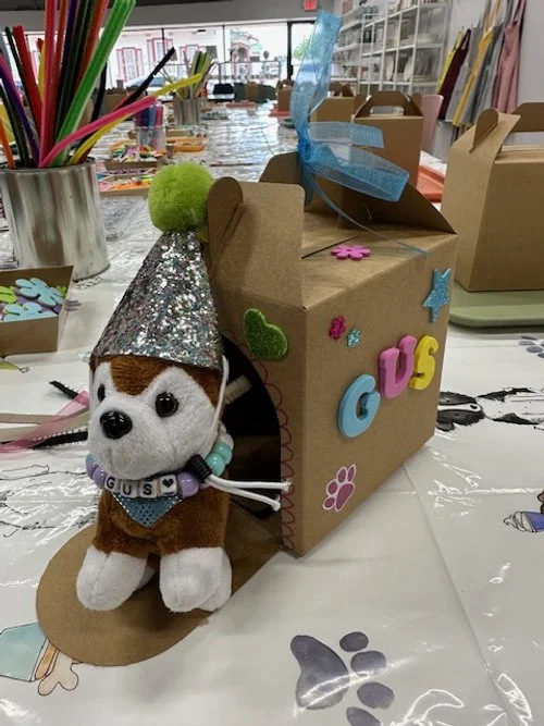 Colorful decorated letters spelling 'Y' and 'M' with various paper decorations, pom-poms, and sequins on a brown background.