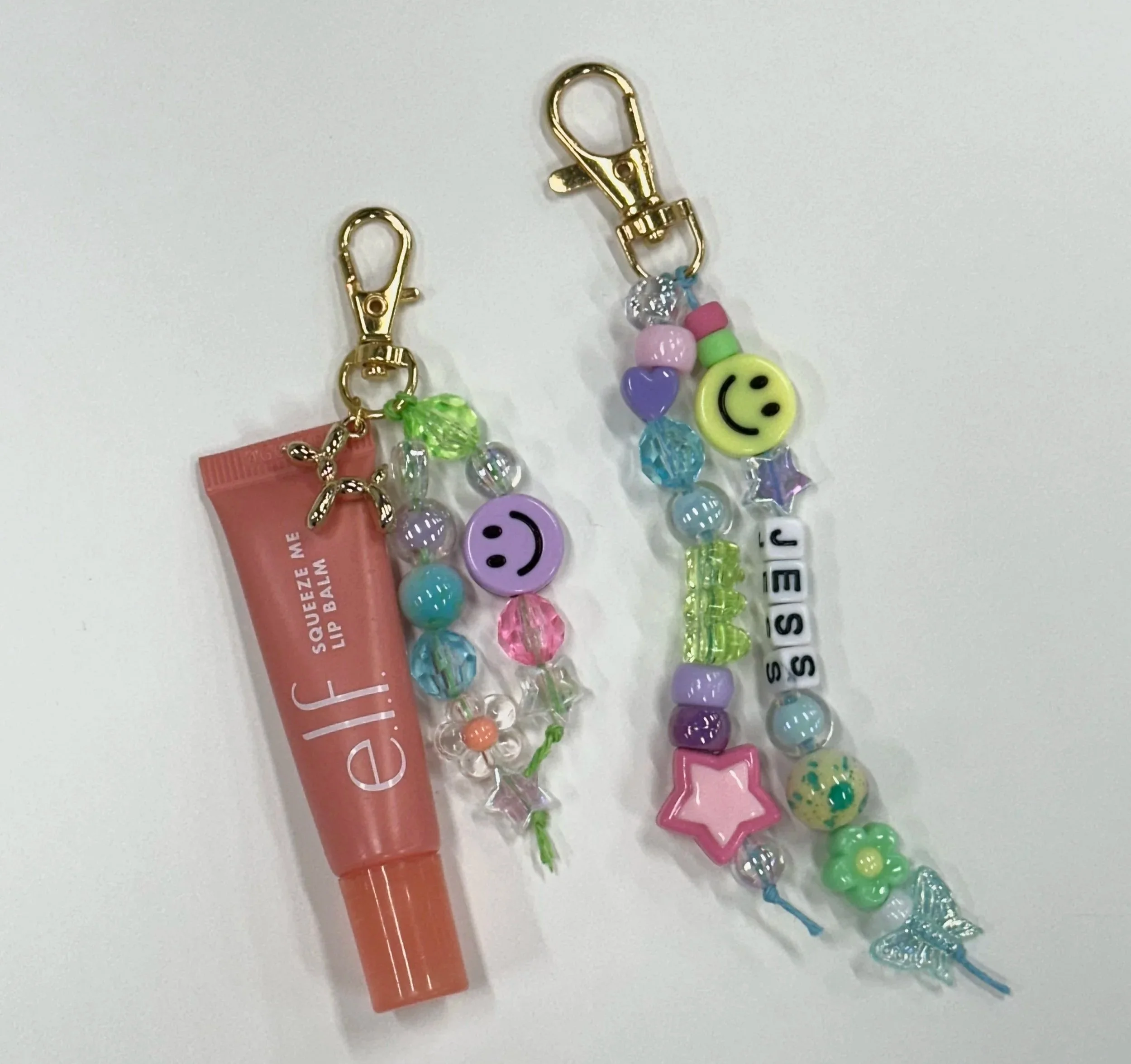 Table with multiple pink bead design boards and clear plastic containers filled with colorful beads and jewelry-making supplies.